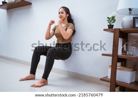portrait of young asian woman squating against the wall at home Royalty-Free Stock Photo #2185760479