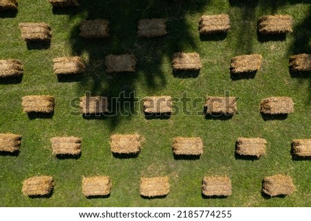 Seats and tables made from straw bales for event and party laid on lawn yard. Furniture made of pallets and straw bales. Aerial drone shot. Beautiful patterns