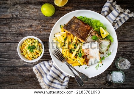 Fish dish - fried halibut with French fries and lemon on wooden table 