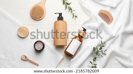 Bottles of shampoo, comb, towels and brush on white wooden background, top view Royalty-Free Stock Photo #2185782009