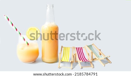 Beach fruit cocktail with a slice of lemon on a light blue background and miniature wooden deck chairs.  The concept of summer vacation, cold drinks.  Close-up, background image.