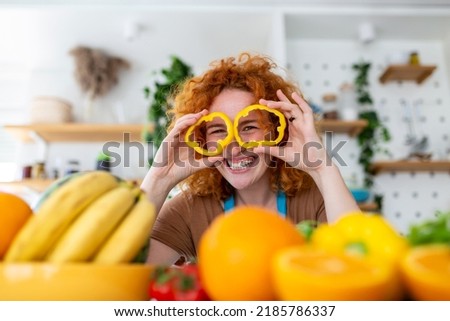 Photo of young woman smiling while cooking salad with fresh vegetables in kitchen interior at home
