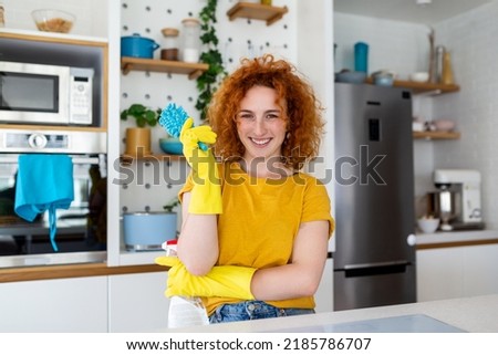 Young woman doing house chores holding cleaning tools. Woman wearing rubber protective yellow gloves, holding rag and spray bottle detergent. It's never too late to clean