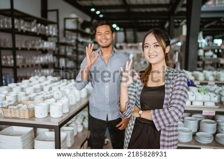 Beautiful asian woman smiling while standing with okay hand gesture in houseware store