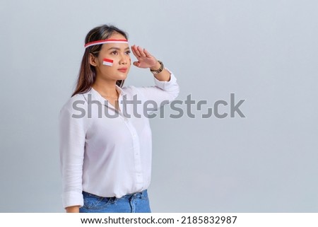 Happy young Asian woman salute gesture with copy space isolated on white background. Indonesian independence day concept Royalty-Free Stock Photo #2185832987