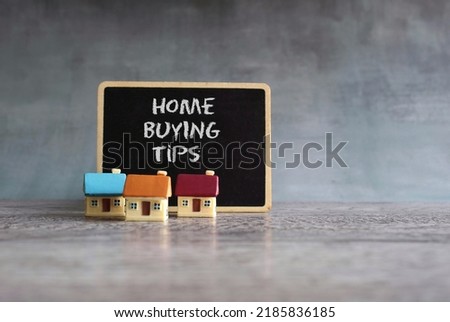 Toy houses and chalkboard with text HOME BUYING TIPS. Home ownership, real estate, property concept