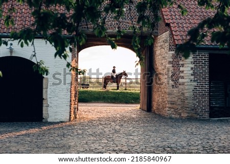 glimpse of a typical medieval European farm building - rider on horseback in the background