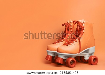 Pair of stylish quad roller skates on orange background. Space for text Royalty-Free Stock Photo #2185851423