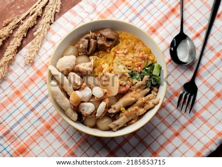 Indonesian Traditional Food Spicy Seblak Soup with Meatball, Chicken Feet, Chips and Vegetables Served on The Orange Pleated Napkin Royalty-Free Stock Photo #2185853715