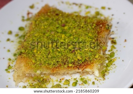 Knefe, traditional turkish dessert from Hatay. A close-up picture of kunefe. Pistachios on the kunefe. Kunefe.