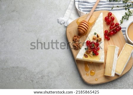 Brie cheese served with currants, walnuts and honey on light table, flat lay. Space for text Royalty-Free Stock Photo #2185865425