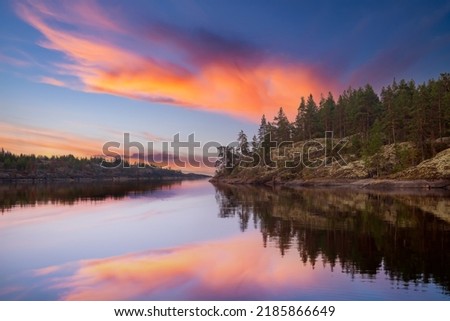 Karelian landscapes. Ladoga lake. Regions Russia. Pine trees on shore Lake Ladoga. Sunset in wild. Rocky coast Karelian lakes. Pine forest is reflected in water. Karelian Republic. Russian Federation Royalty-Free Stock Photo #2185866649