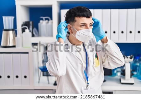 Young non binary man scientist wearing medical mask at laboratory