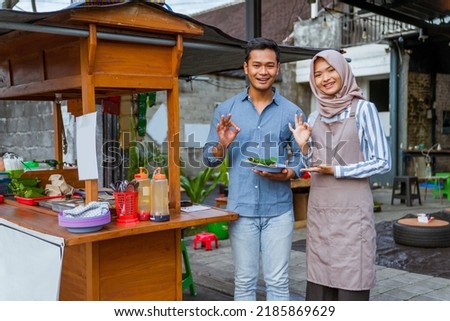 muslim couple ordering food to break fasting in traditional food market stall served by the seller Royalty-Free Stock Photo #2185869629