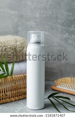 Dry shampoo spray, towels and wooden hairbrush on light grey table