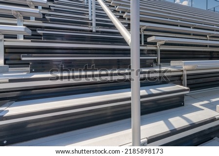 Close-Up of empty metal stadium bleacher seats along aisle with steps and railing.
