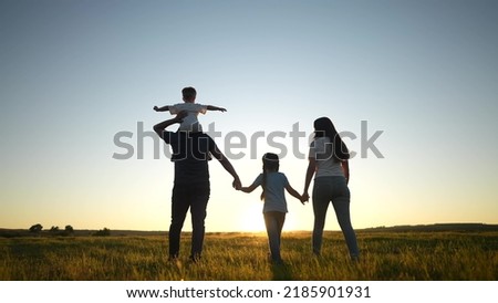 people in the park. happy family walking silhouette at sunset. mom dad and daughters walk holding hands in the park. happy family childhood dream concept. sun parents and children go back silhouette