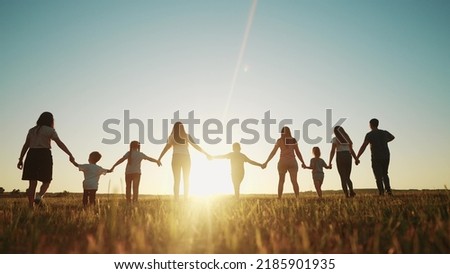 community large family in the park. a large group of people holding hands walking silhouette on nature sunset in the park. big family kid dream concept. people in the park. large sunlight family Royalty-Free Stock Photo #2185901935