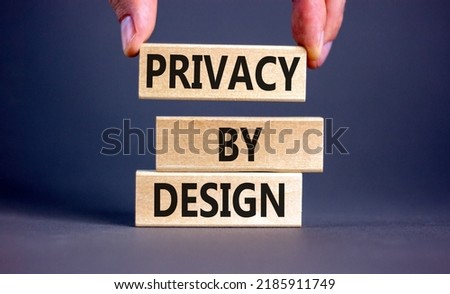 Privacy by design symbol. Concept words Privacy by design on wooden blocks on a beautiful grey table grey background. Businessman hand. Business, finacial and privacy by design concept. Copy space.