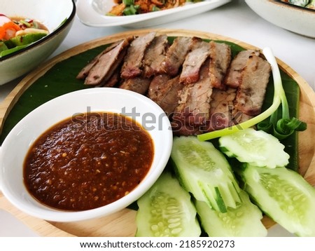 Picture of a dish called grilled beef with spicy sauce. Beautifully arranged in a wooden dish