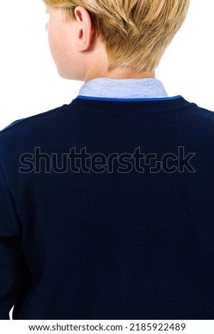 Boy, teeneger posing in a school uniform on a white background. The boy stands with his back to the camera demonstrating clothes from behind. Vertical photo