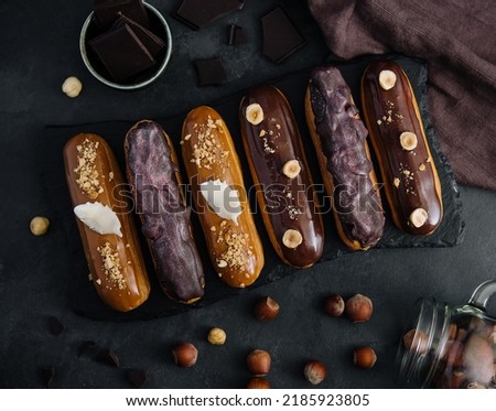 Sweet chocolate eclairs on black wooden board