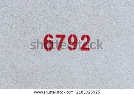 Red Number 6792 on the white wall. Spray paint.
