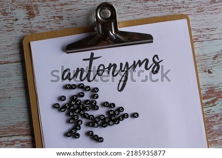 Top view image of paper clipboard with text antonyms and alphabet beads. 