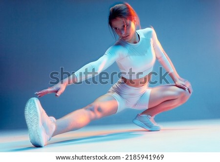 Pilates workout. Fit sports girl stretching legs, hips muscles, squatting. Fitness training, wellness. Long exposure Royalty-Free Stock Photo #2185941969