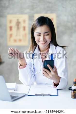 Asian female doctor using laptop computer online video call remote talking to patient.