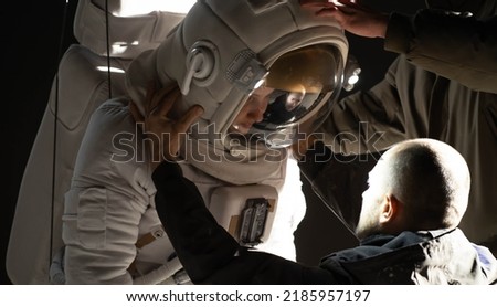 Behind the scenes - Caucasian female stuntwoman wearing a spacesuit being prepared for the shot Royalty-Free Stock Photo #2185957197