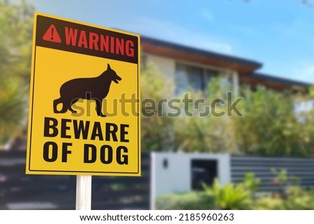 A Beware of Dog Sign in front of a gated home. Warning to visitors or burglars. Security and protection in a residential home concept. Royalty-Free Stock Photo #2185960263