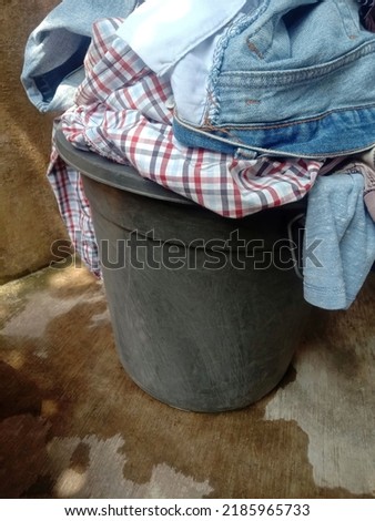 Pile of dirty clothes in black bucket.