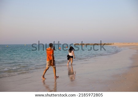 Young man takes picture of his girlfriend at the beach in Dubai. Summer romantic walk