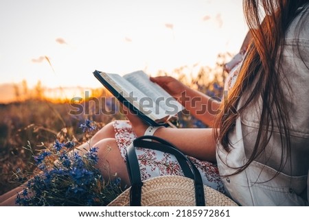 Christian woman holds bible in her hands. Reading the Holy Bible in a field during beautiful sunset. Concept for faith, spirituality and religion. Peace, hope Royalty-Free Stock Photo #2185972861