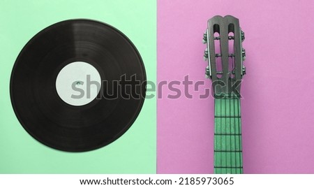 Acoustic guitar neck, vinyl record on pink green background. Musical concept. Minimalism. Top view. Flat lay