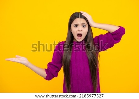 Funny teenager child points aside with cheerful expression, shows amazing at blank empty space. Advertisement and mockup. Surprised emotions of young teenager girl.