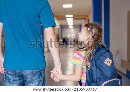 Back to school. Child with father holding hands in school hallway. Happy kid going to first grade. Little girl with backpack indoors. Concept of confidence, support, togetherness. First day at Royalty-Free Stock Photo #2185980767