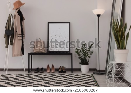 Stylish hallway room interior with bench, shoes, clothes rack and floor mirror