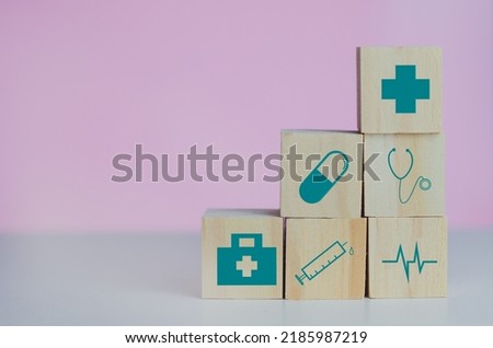 Wooden cubes block with insurance health car medical symbol on the pink background and copy space.