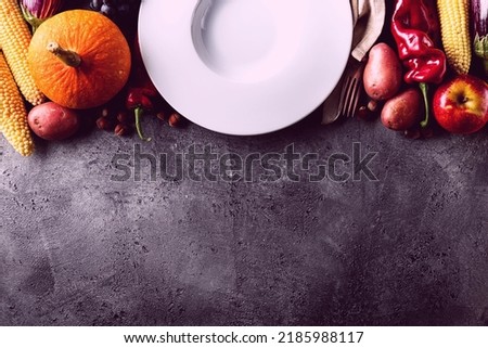Seasonal Harvest Autumn Concept. Empty Plate with Tasty appetizing fresh autumn seasonal vegetables fruits on grey background top view above copy space Royalty-Free Stock Photo #2185988117