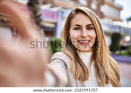Young blonde woman smiling confident make selfie by the smartphone at street