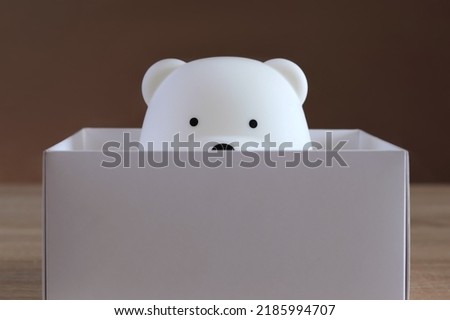 White toy bear in a white box on a wooden background