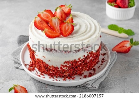 Red velvet cake with fresh strawberries. Festive layered cake from red sponge cakes and cream cheese frosting, American cuisine Royalty-Free Stock Photo #2186007157