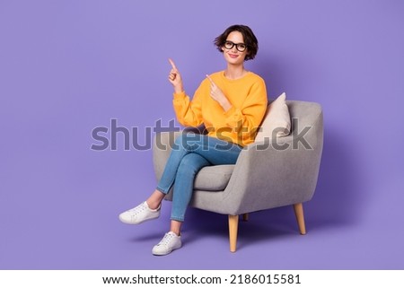 Portrait of attractive cheerful girl sitting demonstrating copy space ad isolated over violet lilac color background Royalty-Free Stock Photo #2186015581