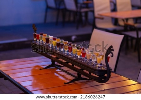 Glass stacks are filled with different drinks as an advertisement in a drinking establishment, a bar on the street.