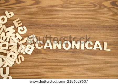 Word CANONICAL written with solid letters on a board. Wooden letters on wooden background. Royalty-Free Stock Photo #2186029537