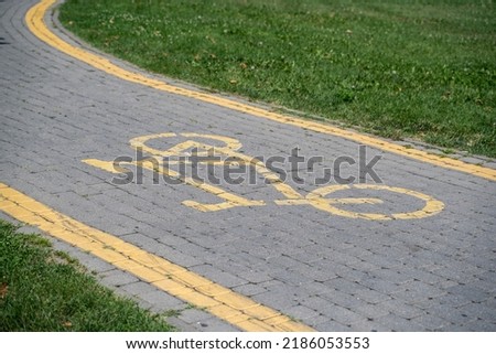 Bicycle path with a bicycle sign made of paving stones among a lawn of green grass