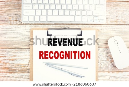 REVENUE RECOGNITION text on a clipboard with keyboard on wooden background