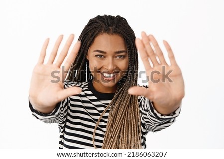 Image of smiling black woman imaging, picturing moment, looking through hand frames, creating moment something, standing over white background